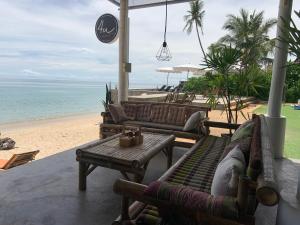 a patio with couches and a table and the beach at 4U Resort Samui in Lamai