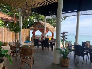 a restaurant with tables and chairs and the ocean at 4U Resort Samui in Lamai