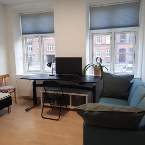 a living room with a desk with a computer and two windows at 1- Bed Private room in apartment in Odense
