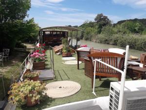 una terraza con sillas, mesas y flores en un barco en Peniche Caroline, en Capestang