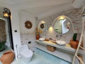 a bathroom with two sinks and two mirrors at OMA WATU DOME VILLAS in Pacitan