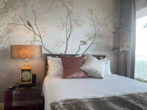 Schlafzimmer mit einem Bett mit weißer Bettwäsche und Blumentapete in der Unterkunft Sydney Cosmopolitan CBD Apartment in Sydney