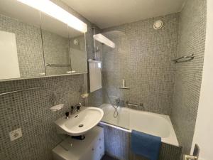 ein Badezimmer mit einem Waschbecken, einem Spiegel und einer Badewanne in der Unterkunft Résidences Kandahar in Crans-Montana