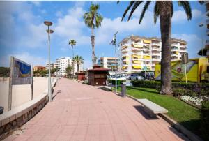 a sidewalk with a bench and palm trees and buildings at One Bedroom Flat in Fenals Lloret de Mar for 4 People in Lloret de Mar