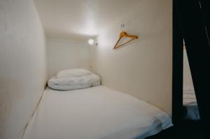 um pequeno quarto com uma cama e um cabide na parede em unito light SHIMBASHI em Tóquio
