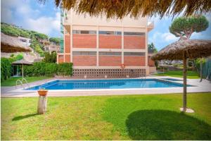 uma casa com piscina em frente a um edifício em One Bedroom Flat in Fenals Lloret de Mar for 4 People em Lloret de Mar