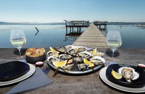 a table with a plate of oysters and glasses of wine at Charmante suite indépendante avec cave à vin in Cournonsec