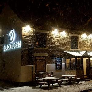 um grupo de mesas de piquenique na neve à noite em The Stables at The Black Horse em Willington