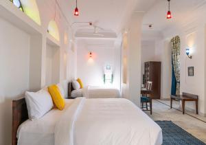 a white bedroom with two beds and a desk at Bloom Boutique - Chelon Haveli in Jaipur
