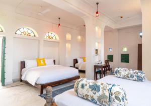 um quarto com duas camas, uma mesa e cadeiras em Bloom Boutique - Chelon Haveli em Jaipur mais 39 fotografias