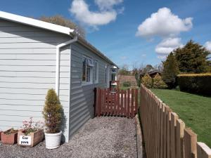a small house with a fence next to a yard at Family friendly rural lodge in Truro +5 photos