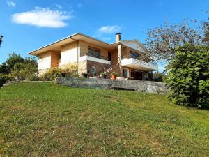 una casa grande en una colina con un campo de hierba en La Casuca de La Franca, en La Franca