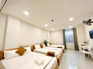 a hotel room with three beds and a table at Anh Đào Hotel in Vung Tau