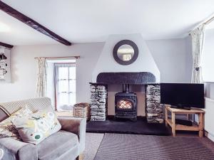 a living room with a fireplace and a couch at Stable End Cottage in Bouth