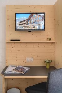 a television on a wooden wall with a desk at Jungfrau Lodge, Annex Crystal in Grindelwald