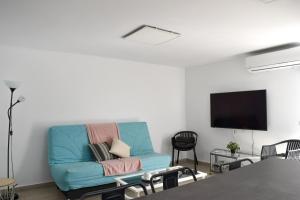 a living room with a blue couch and a flat screen tv at Casa Sabare in Guinea