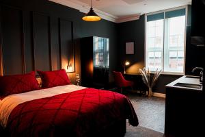 czarna sypialnia z czerwonym łóżkiem i biurkiem w obiekcie The Old Post Office Warrington by Deuce Hotels w mieście Warrington