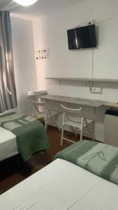 Habitación con 2 camas, mesa y escritorio. en Casa de Huéspedes Almansa, en Madrid