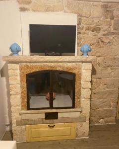 einen Steinkamin mit einem TV darüber. in der Unterkunft La casa di Alessia Largo Torre in Noci