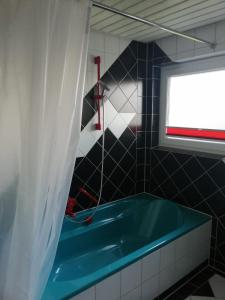 a bathroom with a blue tub and a window at Haus Hochwald in Rottweil