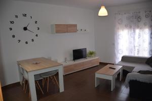 sala de estar con mesa y reloj en la pared en Apartamento14 Ruidera AguaPlacer, en Ruidera