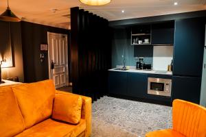 a living room with an orange couch and a kitchen at The Old Post Office Warrington by Deuce Hotels in Warrington