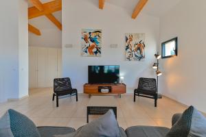 sala de estar con TV y 2 sillas en Villa à l'entrée de Porticcio - Piscine - Vue dégagée, en Cauro