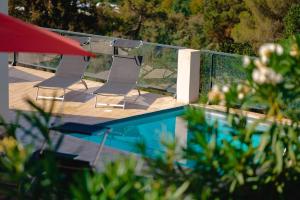 2 sillas sentadas en una terraza junto a una piscina en Villa à l'entrée de Porticcio - Piscine - Vue dégagée, en Cauro