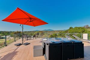 una mesa con una sombrilla roja en una cubierta en Villa à l'entrée de Porticcio - Piscine - Vue dégagée, en Cauro