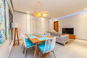 a dining room with a table and chairs and a couch at Penthouse 13 - One Bay Residence with private rooftop terrace and dip in pool in Pereybere