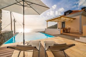 a villa with a swimming pool with two chairs and an umbrella at Villa Escola da Bica in Arco da Calheta