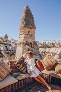 una donna seduta su un mucchio di cuscini di Aza Cave Cappadocia Adult Hotel a Göreme