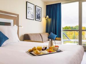 サン・ピエール・デュ・ペレにあるNovotel Senart Golf De Greenparcのホテルのベッドに食料品のトレイ