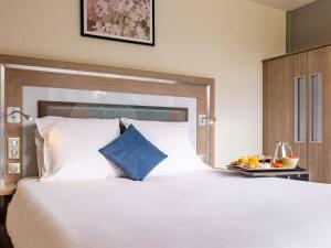 a bedroom with a large white bed and a tray of fruit at Novotel Senart Golf De Greenparc in Saint-Pierre-du-Perray