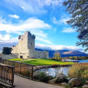 un castillo sentado junto a un cuerpo de agua en Kinvara House, en Killarney