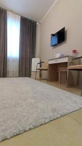 um quarto com uma cama, uma secretária e uma televisão em Station Hostel em Atyrau