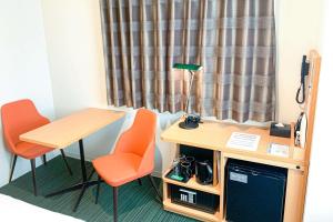 a room with a desk and two chairs and a table at Comfort Hotel Matsuyama in Matsuyama