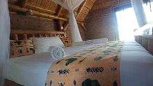 ein Schlafzimmer mit einem weißen Bett mit einer Decke darauf in der Unterkunft NKUNDWA NILE VIEW LODGE in Wanseko