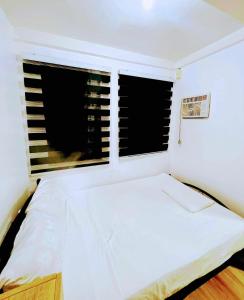 - une chambre avec un lit blanc et 2 fenêtres dans l'établissement Cabuhat Duco Lodge 2, à Naic