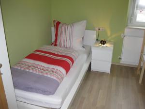 een wit bed met een gestreepte deken op een kamer bij Holiday Home Debacher in Kappel-Grafenhausen
