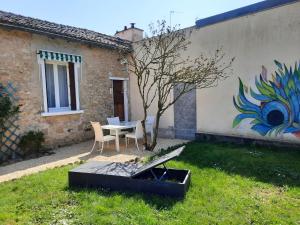 a garden with a table and chairs and a wall with a painting at Maison Cosy in Ligugé