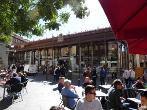 Apartamento en el Mercado de San Miguel في مدريد: مجموعة من الناس يجلسون على الطاولات أمام المبنى