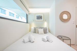 une chambre avec un lit blanc avec des oreillers blancs dans l'établissement SYNTAGMA MINI, à Athènes