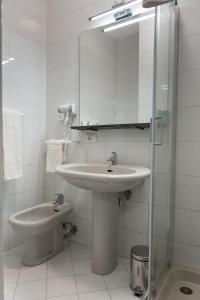 Baño blanco con lavabo y espejo en Hotel del Sole-Aversa, en Aversa