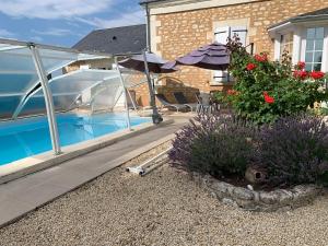 a house with a swimming pool with an umbrella and flowers at La Costonnerie in Leigné-sur-Usseau +4 photos
