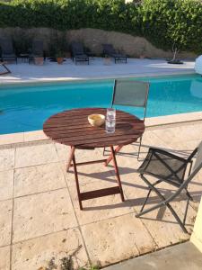 une table en bois et une chaise près de la piscine dans l'établissement Le Marronnier, à Saint-Geniès-de-Fontedit