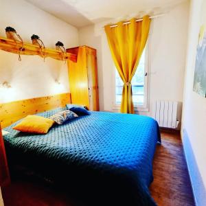 een slaapkamer met een blauw bed en een raam bij Appartement avec piscine & jardin pied de la télécabine in Saint-Gervais-les-Bains