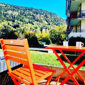 un tavolo e una sedia rossi e arancioni su un balcone di Appartement avec piscine & jardin pied de la télécabine a Saint-Gervais-les-Bains