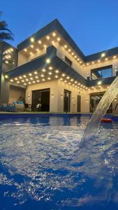 a swimming pool with a fountain in front of a house at Villa Jana chalet - Private Villa - Dead Sea - Jordan in Ash Shāghūr