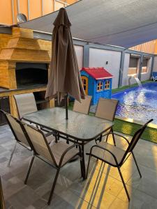 a table and chairs with an umbrella and a swimming pool at Villa Jana chalet - Private Villa - Dead Sea - Jordan in Ash Shāghūr